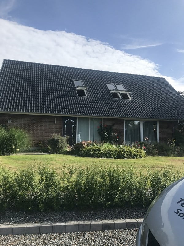 Murstenshus med sort tag og grøn have