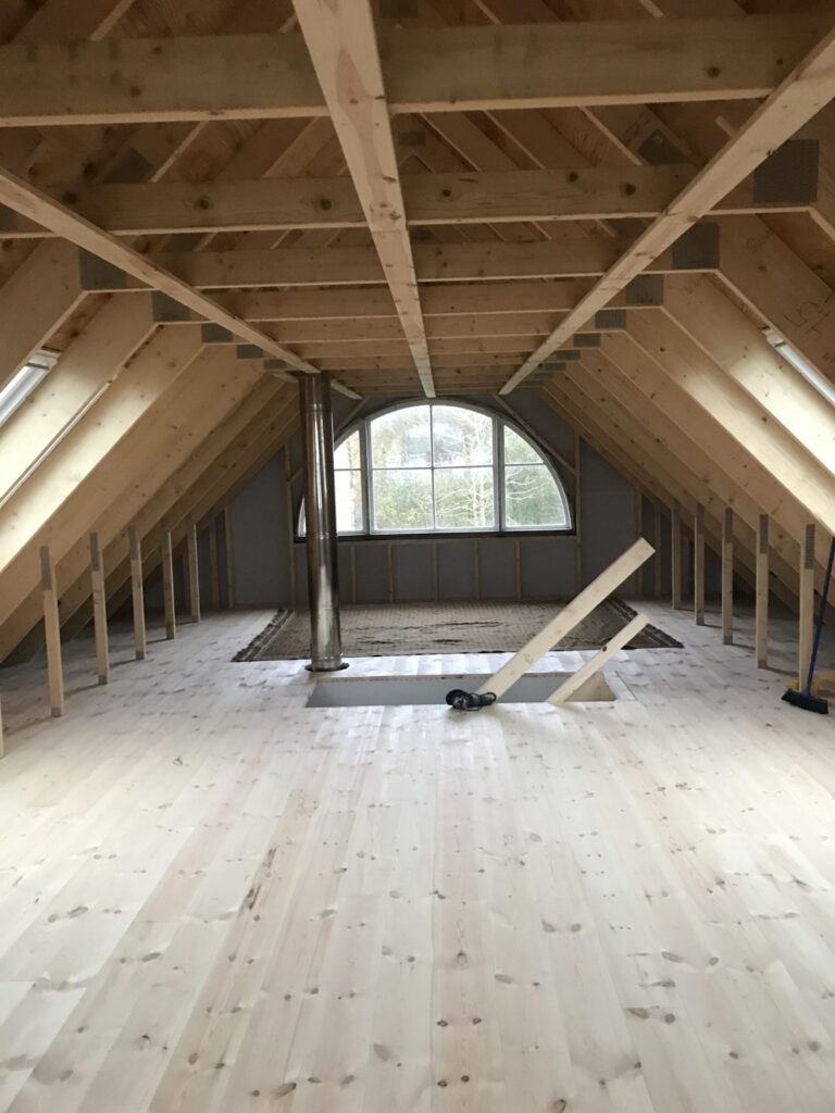 Renovering af lyst trægulv på loft med træbjælker