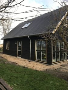 Sort træhus med stort vindue og skråt tag